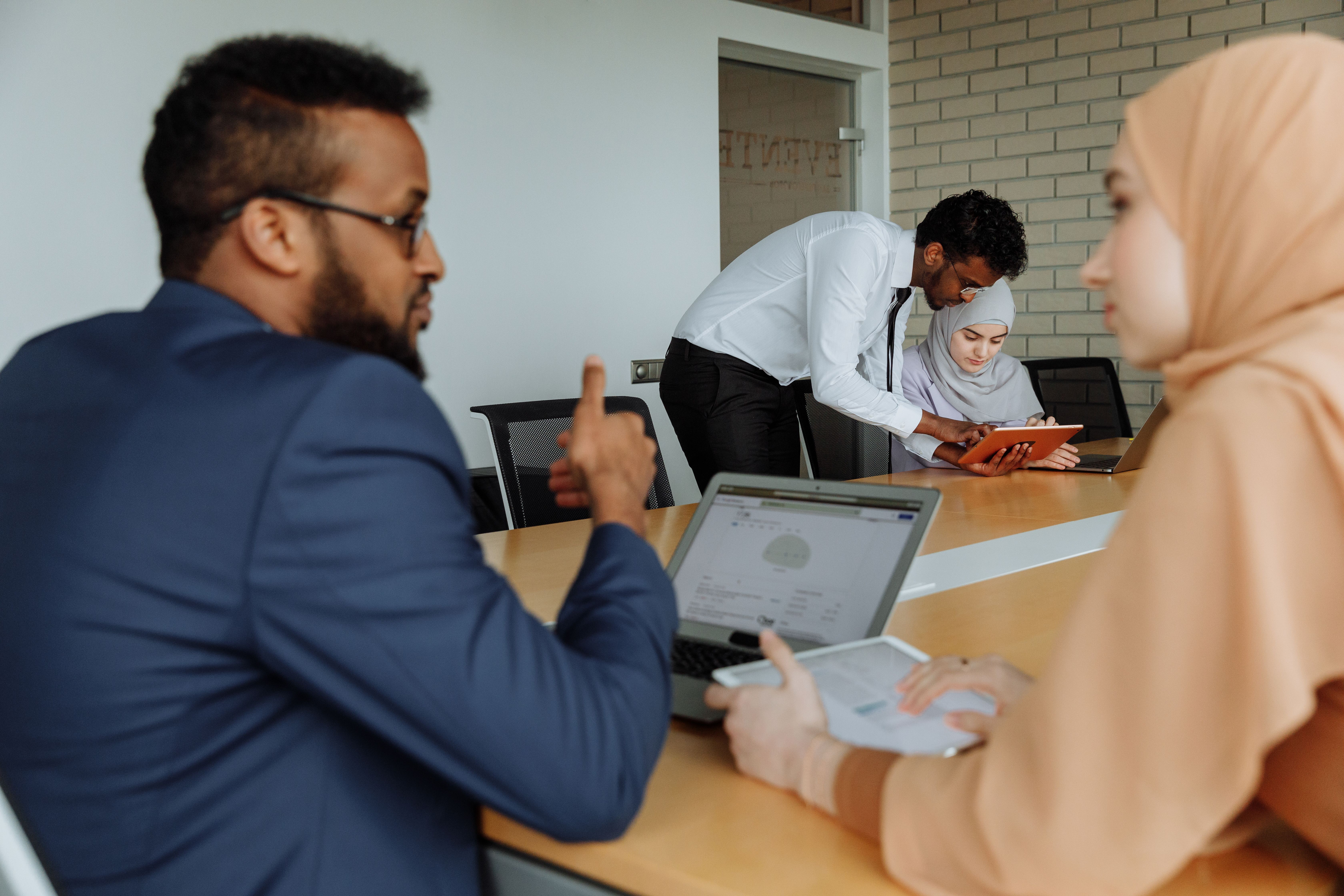 Team reviewing work on laptops in office meeting